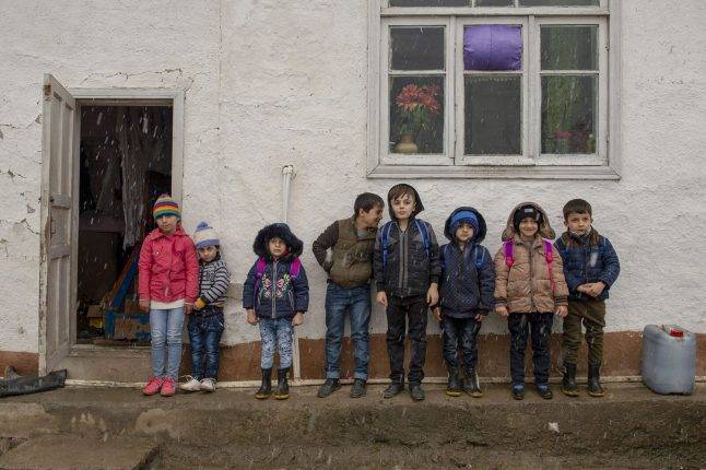 Children gather in front of a designated house to wait for the car to go to school. Photo: Orkhan Azimov