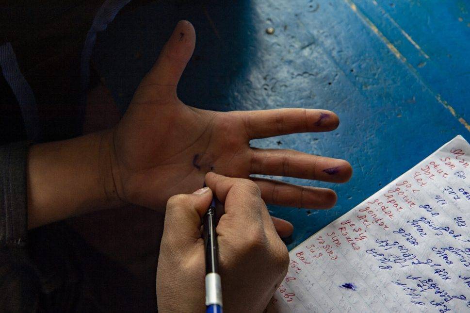 Shindan writes the words his father teaches him. Photo: Orkhan Azimov