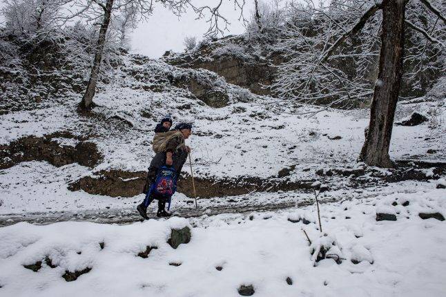 Because of the mud and snow, a grandmother carries her grandson on her back to school. Photo: Orkhan Azimov